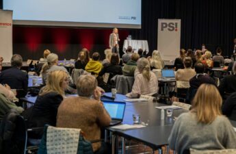 Konferencedeltagere lytter til oplægsholder på scene