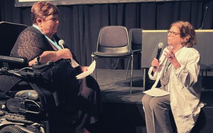 Rollespil på scene. En kvinde i kørestol spiller patient overfor en kvinde i kittel, der spiller læge.