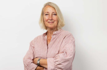 Portræt af PS!-direktør Inge Kristensen med et smil på læben og armene over kors.