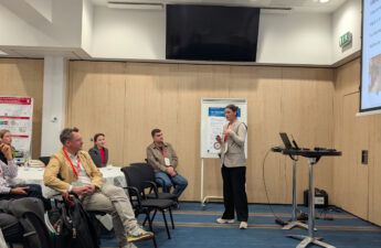 Kvinde står og taler foran et publikum