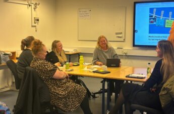 Seks mennesker sidder rundt om et bord og snakker