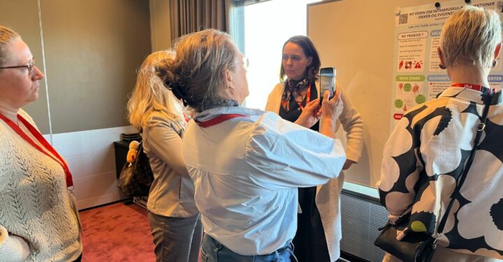 kvinder står og taler sammen foran en plakat