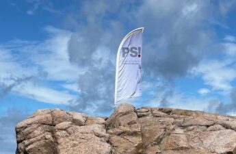 beach-flag med logo for Dansk Selskab for Patientsikkerhed sat fast mellem klipperne på Bornholm
